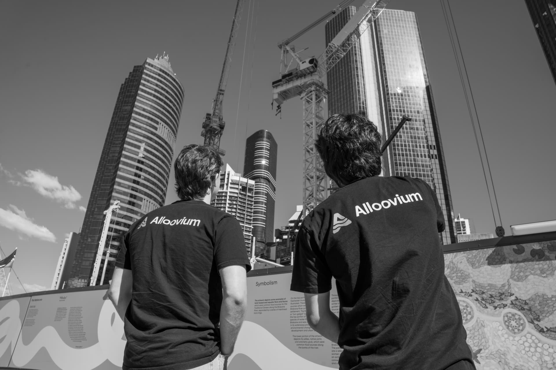 The Alloovium founders on a live construction site, looking up at the towers